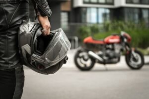 motorcycle rider holding helmet near motorcycle