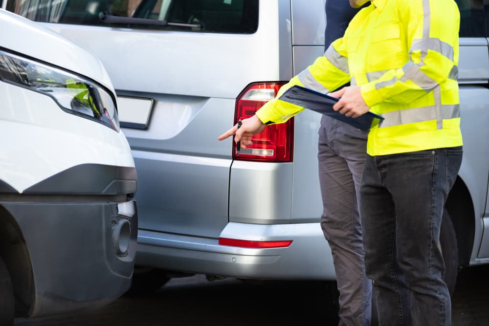 Statute of Limitations for Filing a Car Accident Claim Insurance agent examining a car after an accident, assessing and processing the claim on the street.
