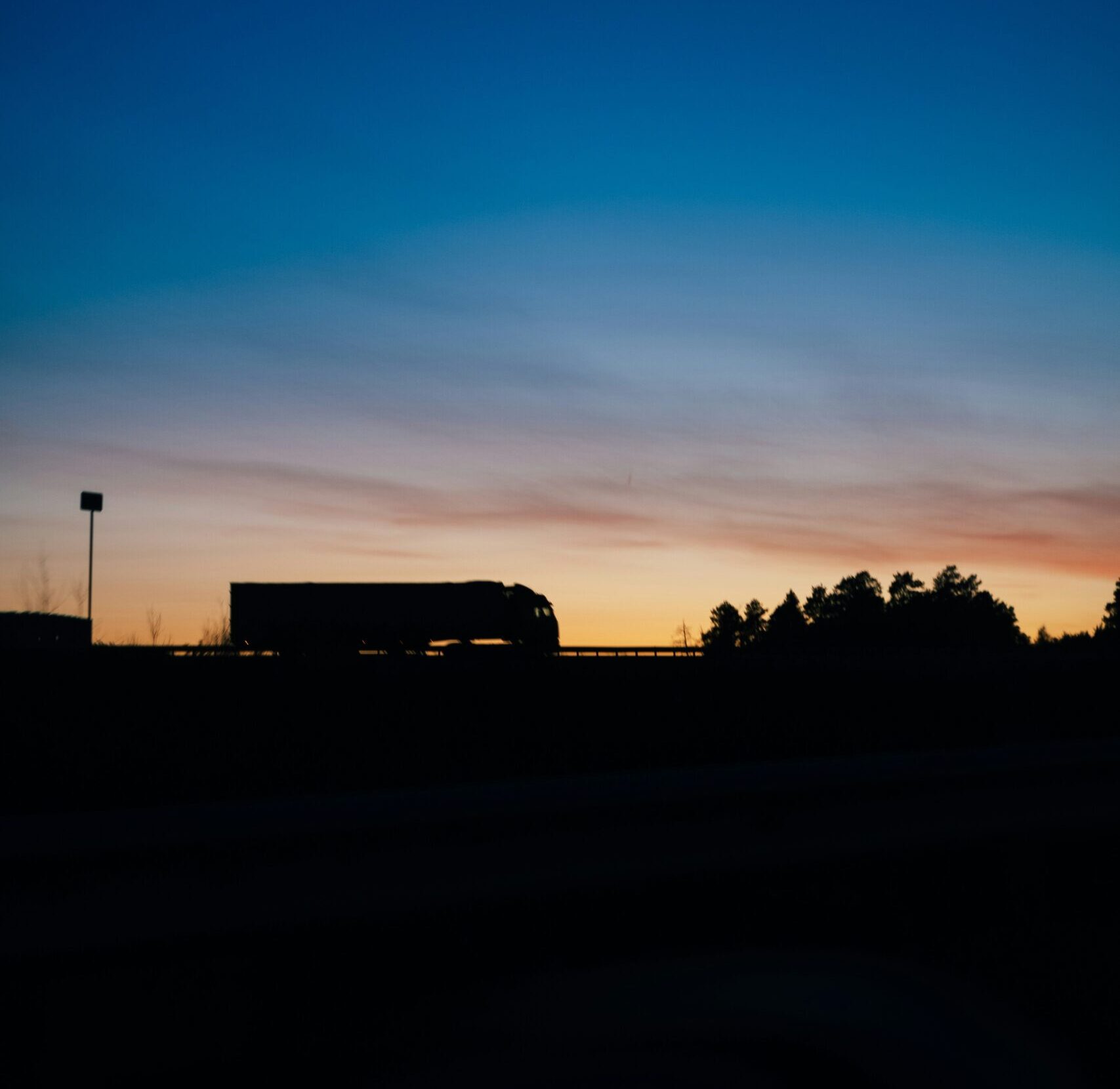 a semi truck travels in the near darkness