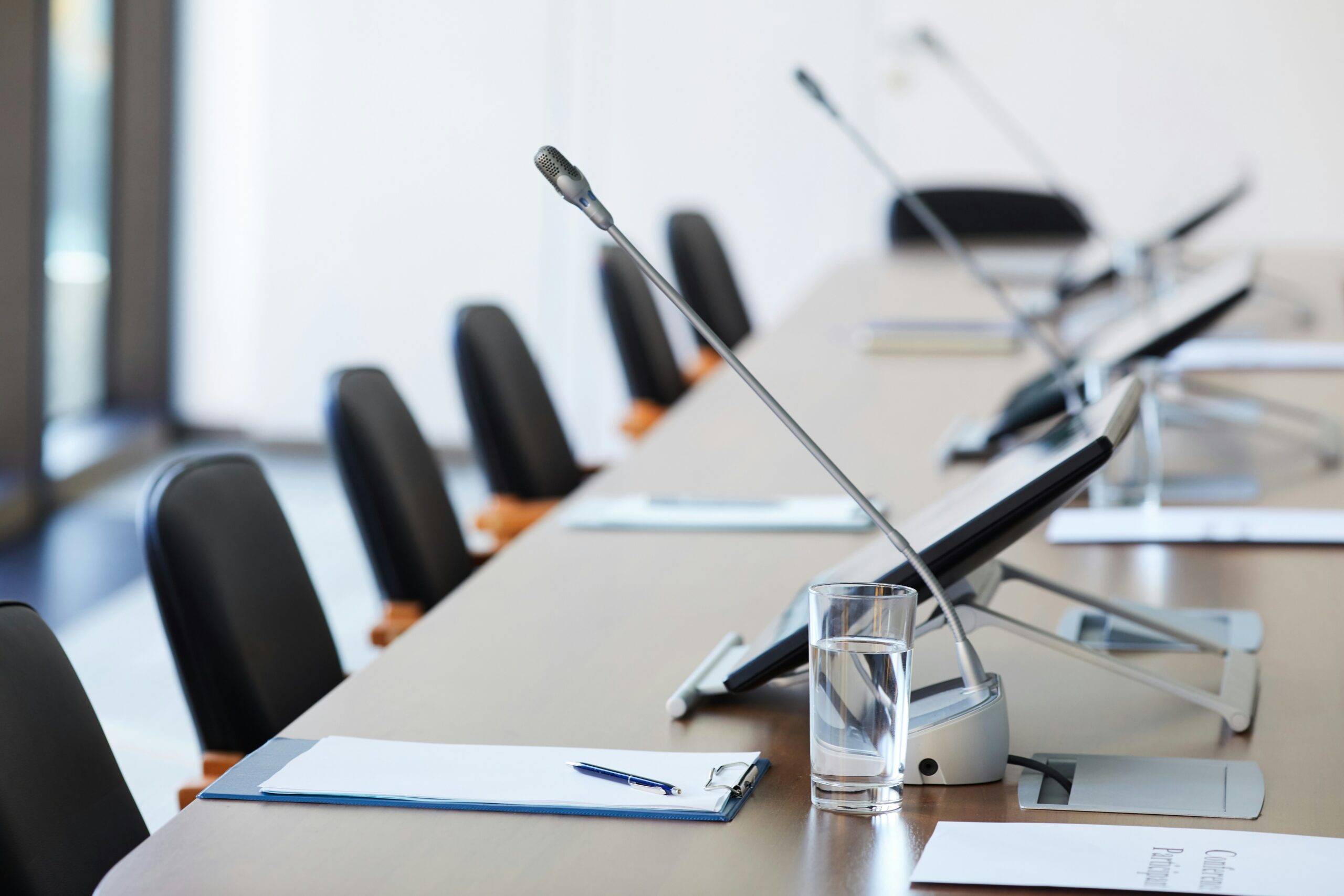 a long table with microphones and tablets, set up for a deposition.