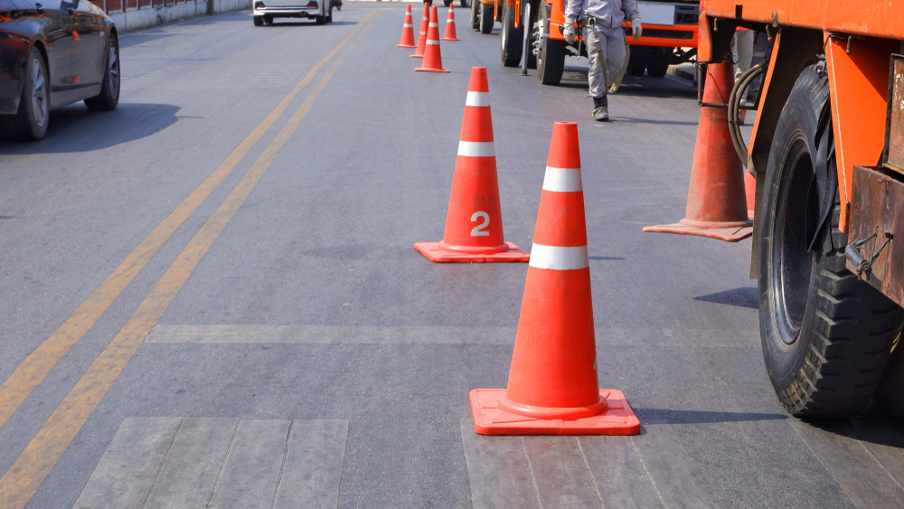 Traffic cones lining a road near a truck and worker